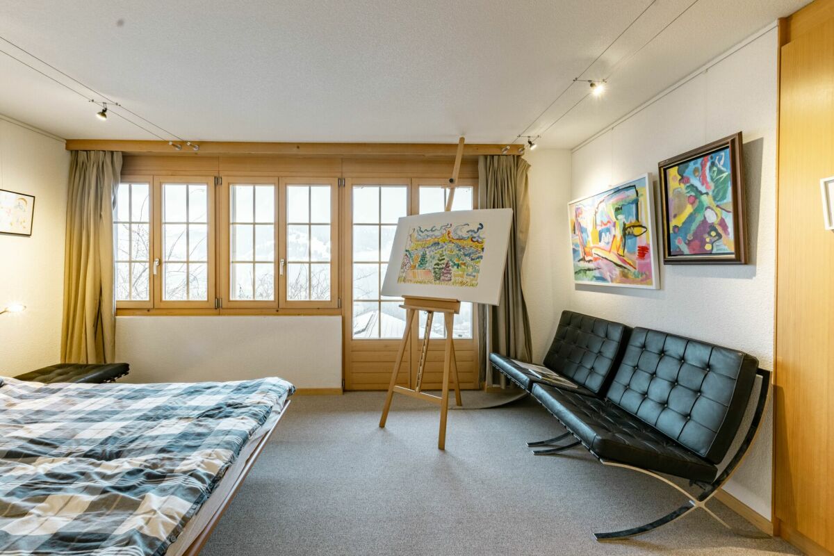Helles Schlafzimmer mit großen Holzfenstern und Kunstwerk