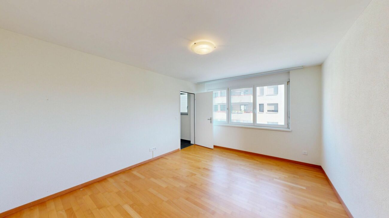 Leeres helles Zimmer mit Fenster und Holzboden