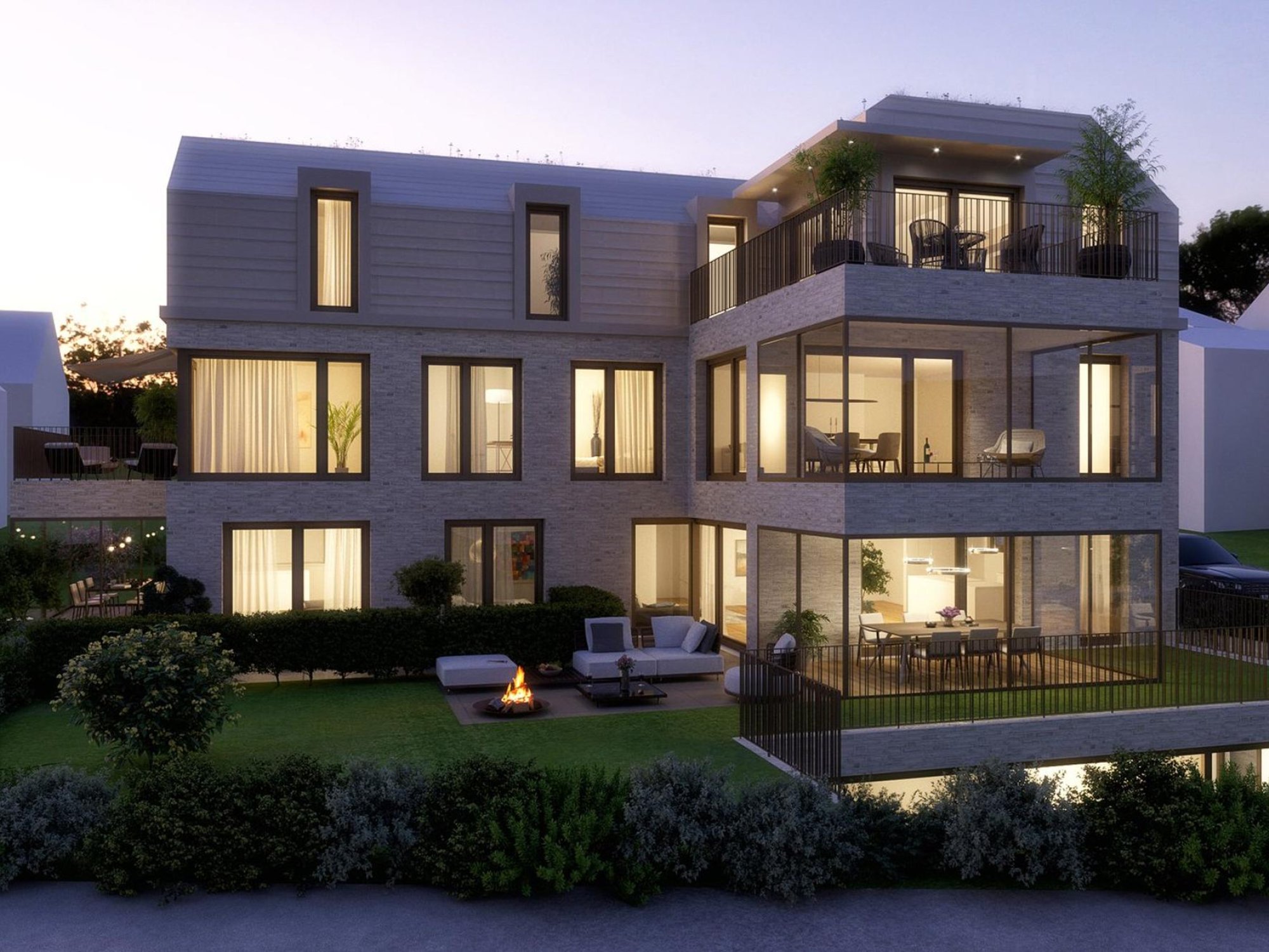 Modernes Mehrfamilienhaus mit Dachterrassen und Garten bei Dämmerung