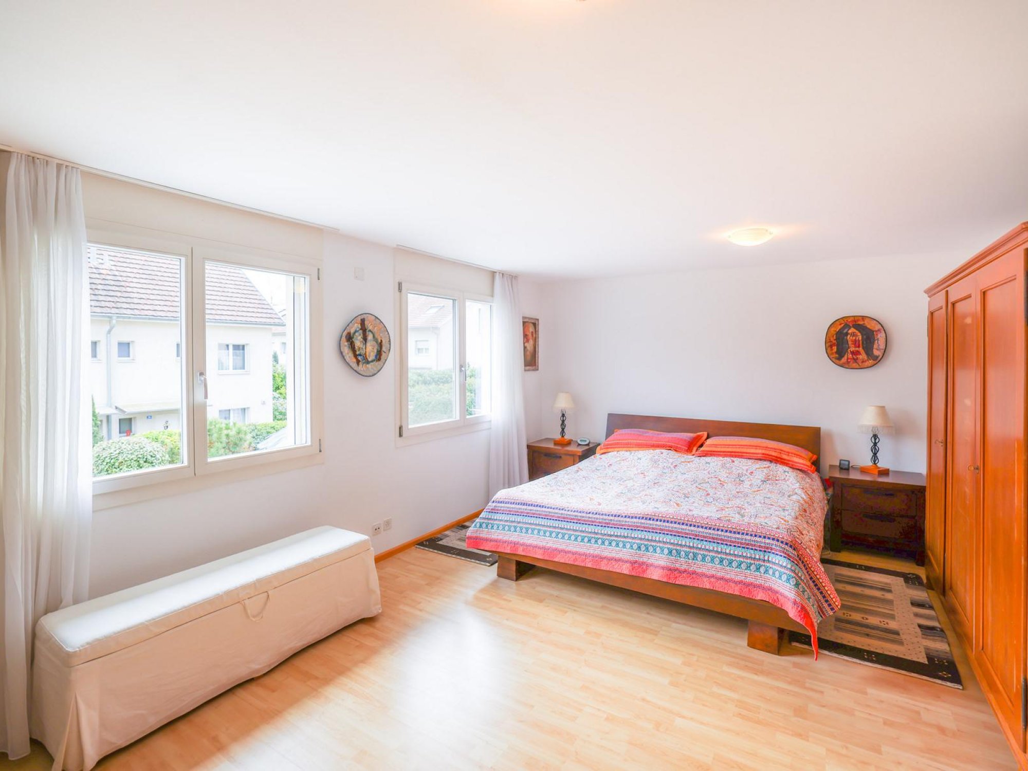 Helles Schlafzimmer mit Doppelbett und großen Fenstern