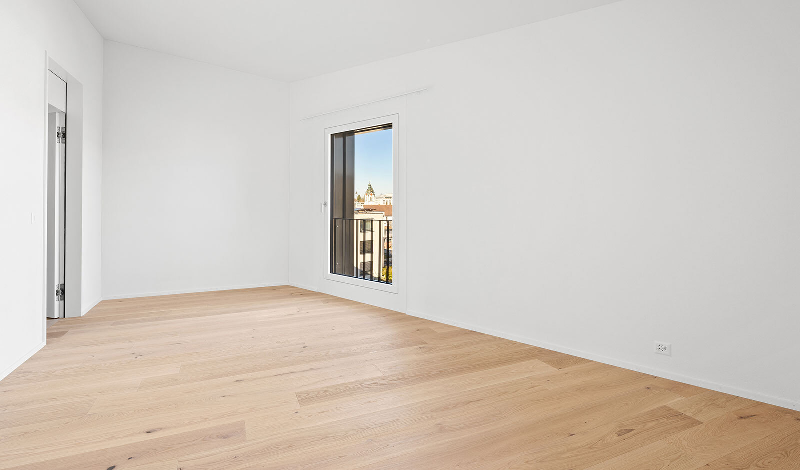 Heller leerer Wohnraum mit Parkett und Ausblick