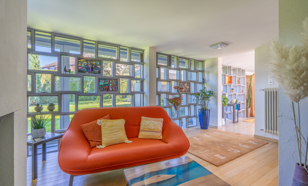 Helles Wohn-/Esszimmer mit großen Fenstern und farbigem Sofa