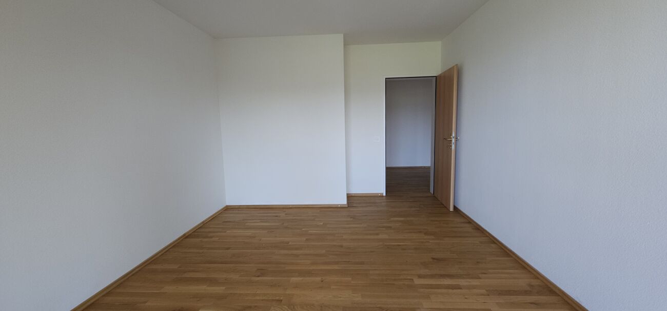Leerer Innenraum mit Holzboden und offener Tür