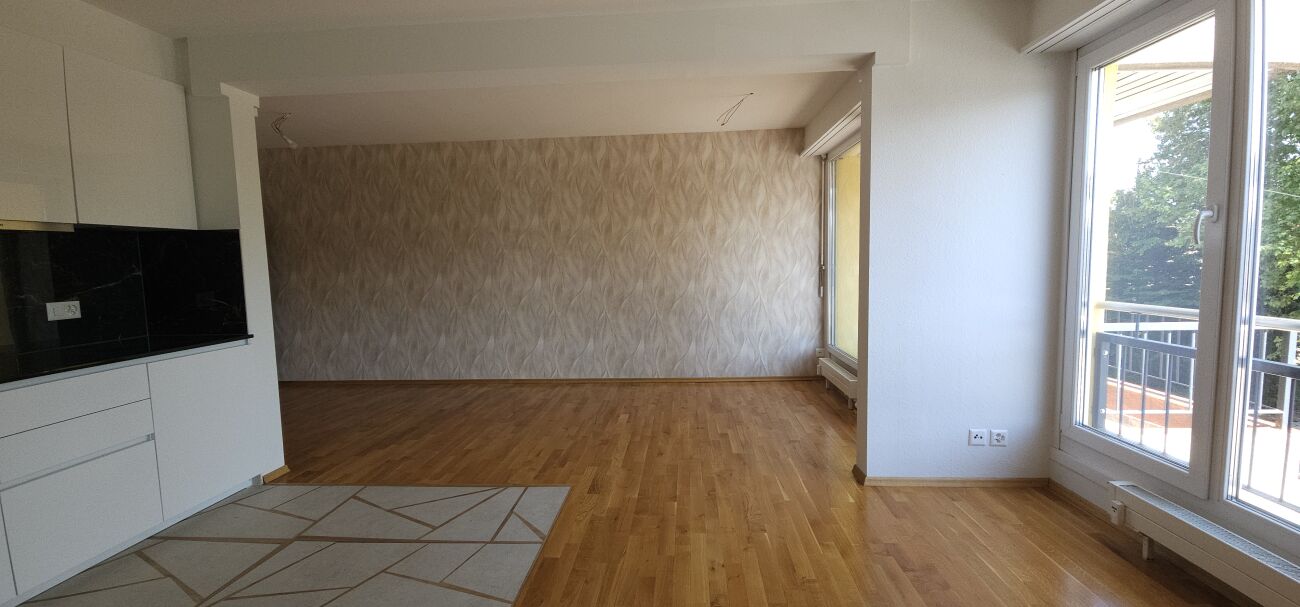 Wohnzimmer mit offener Küchenzone und Balkonblick
