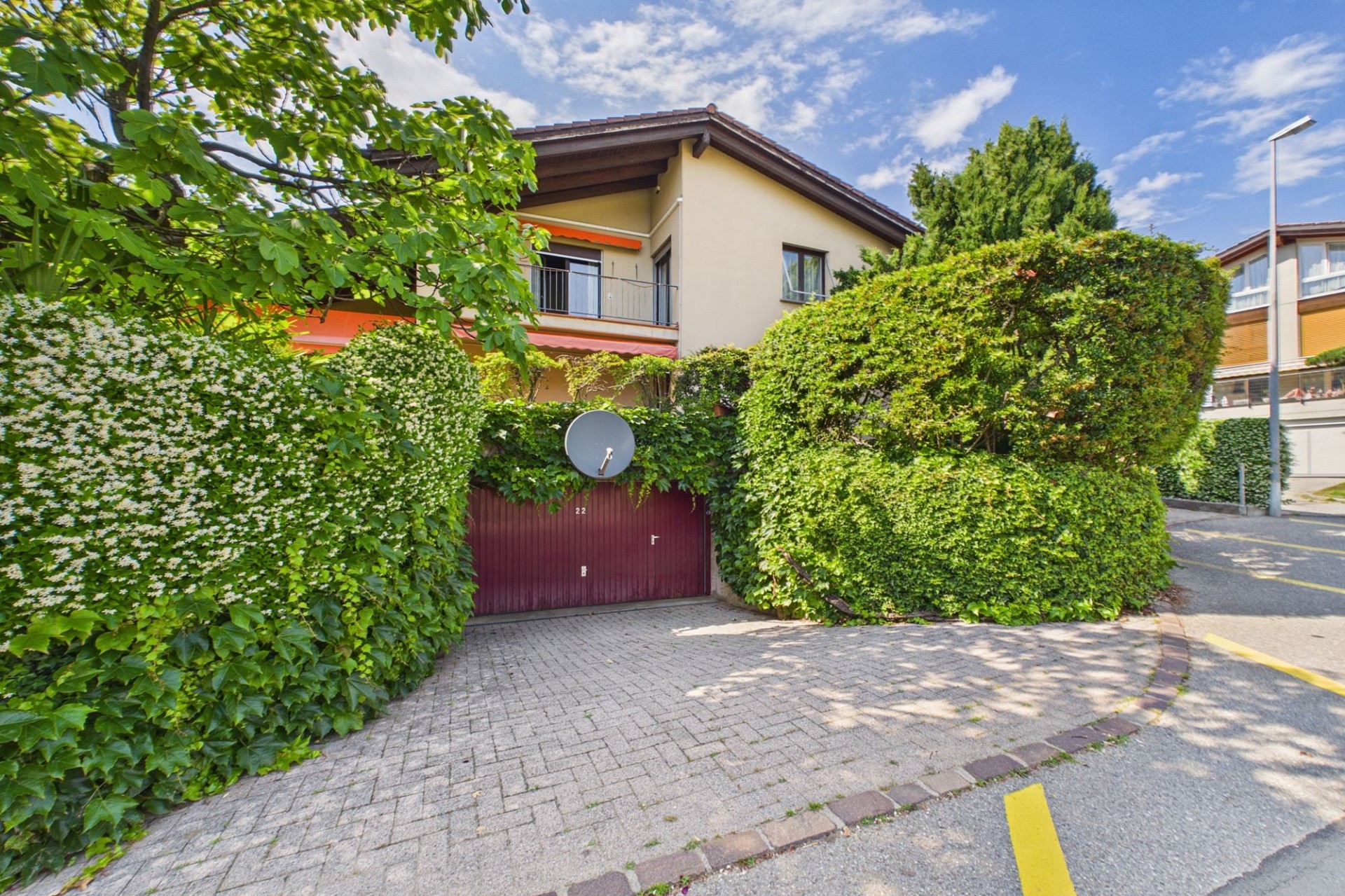 Außenansicht eines begrünten Wohnhauses mit Garage