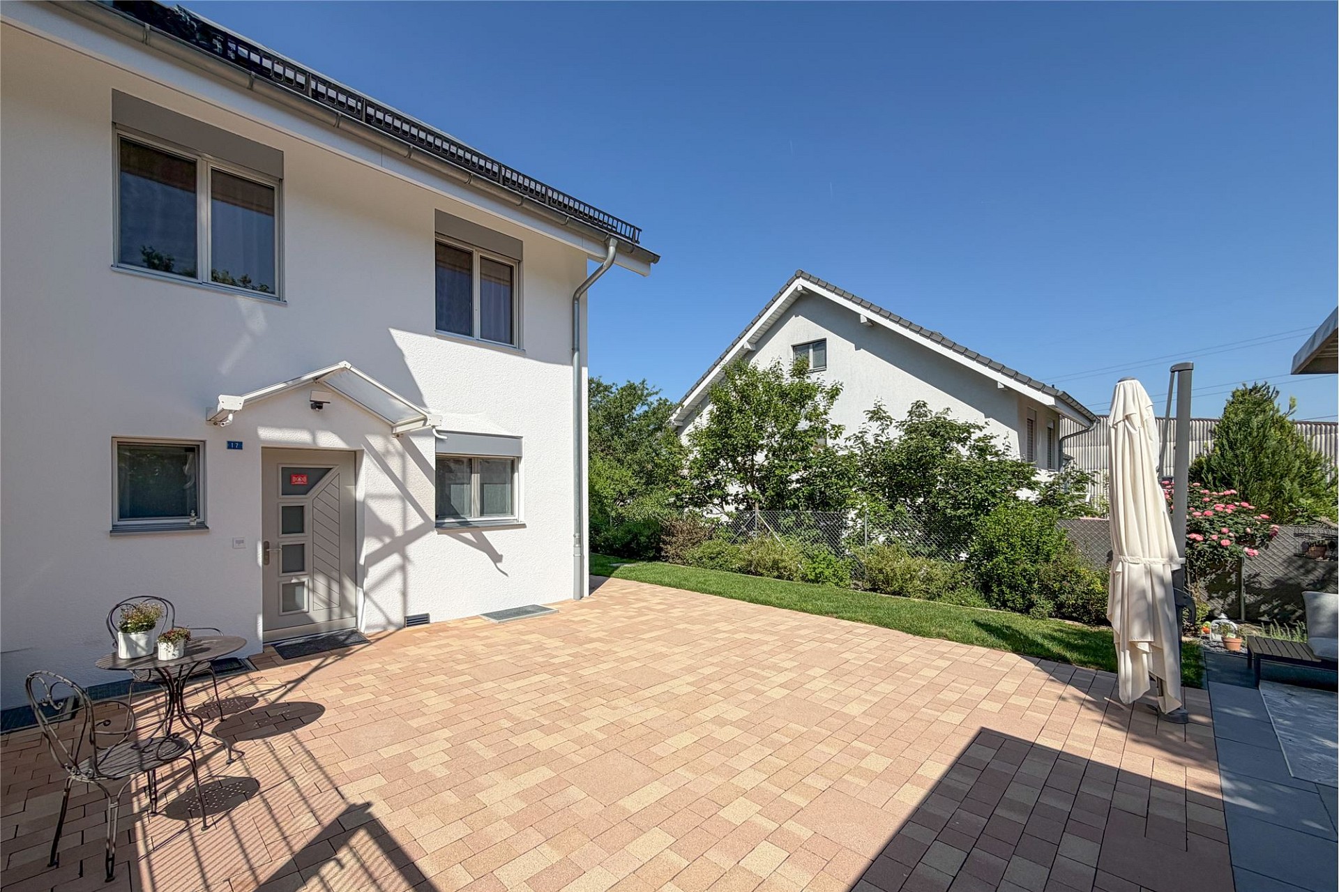 Große gepflasterte Terrasse mit Einfamilienhaus