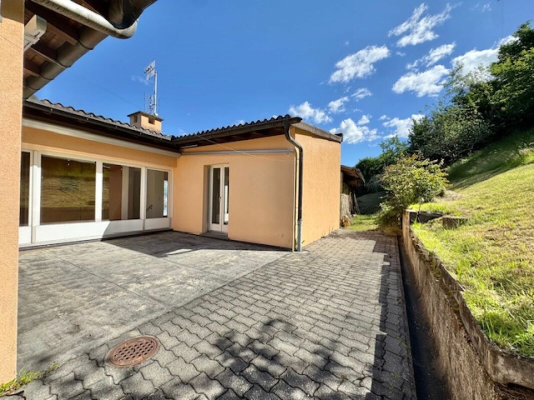 Terrasse mit Hausfassade und Gartenhang
