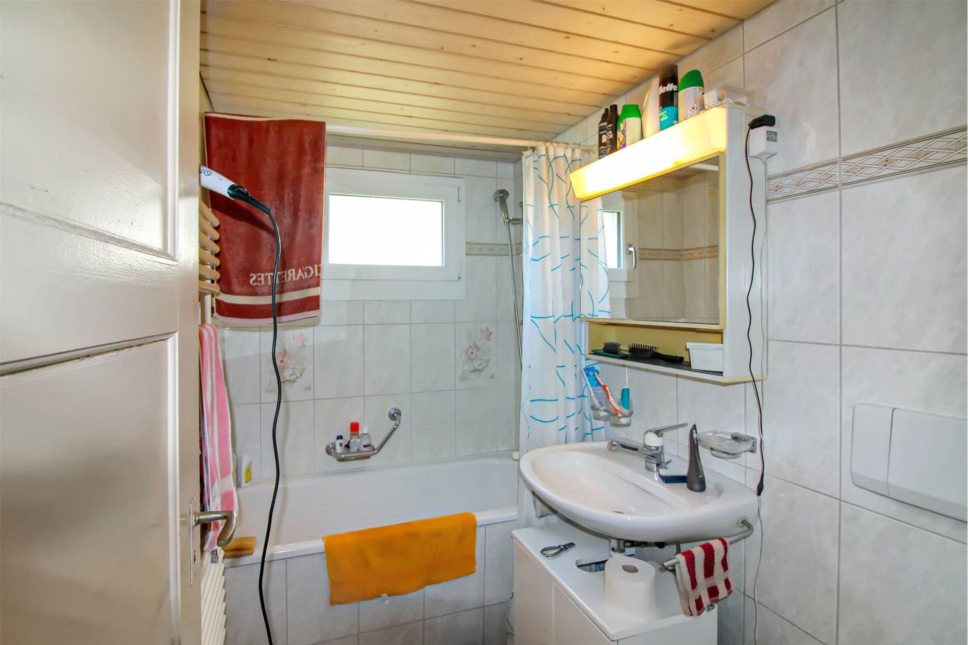 Kleines Badezimmer mit Badewanne und Waschplatz