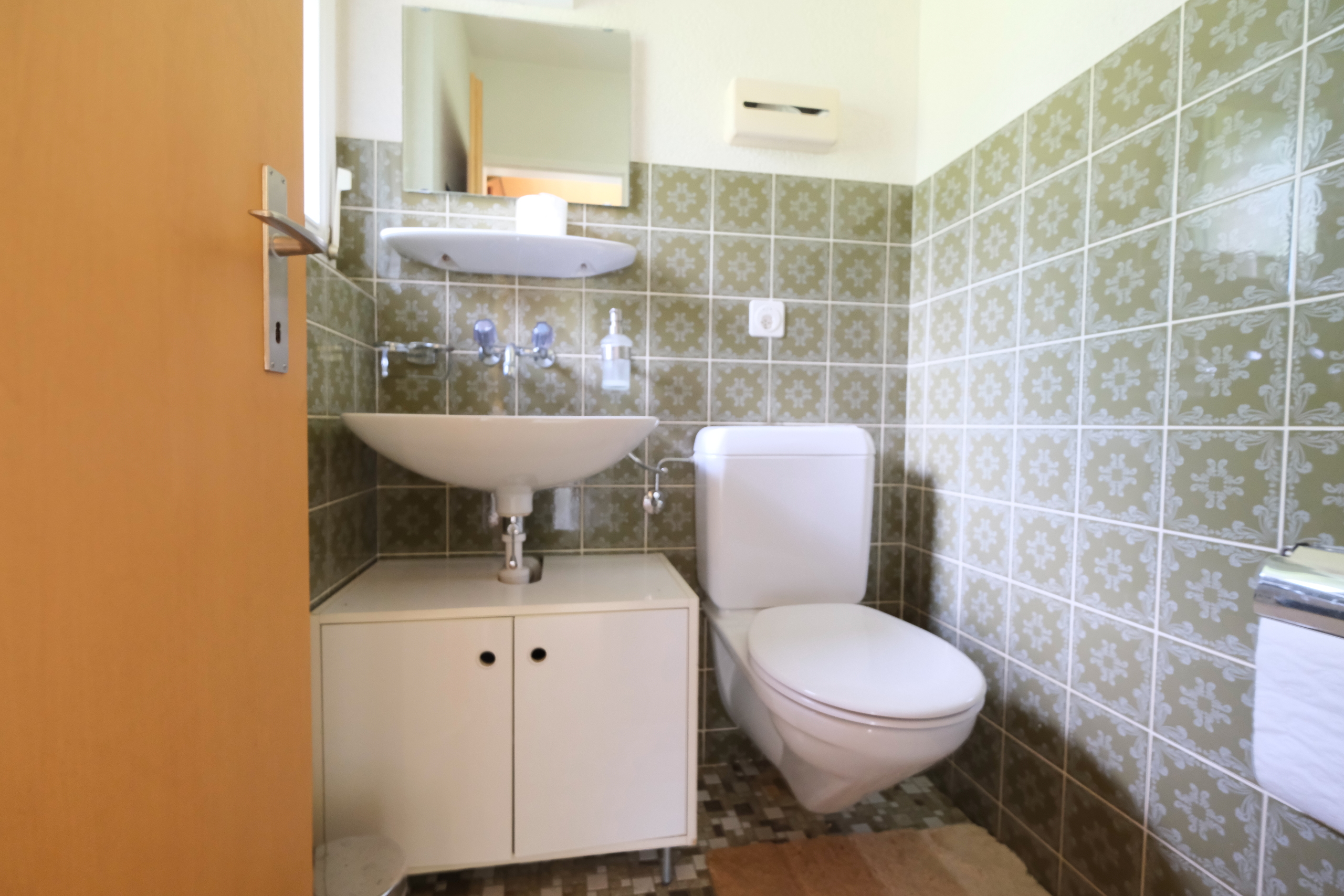 Kleines Gäste-WC mit grün gemusterten Fliesen