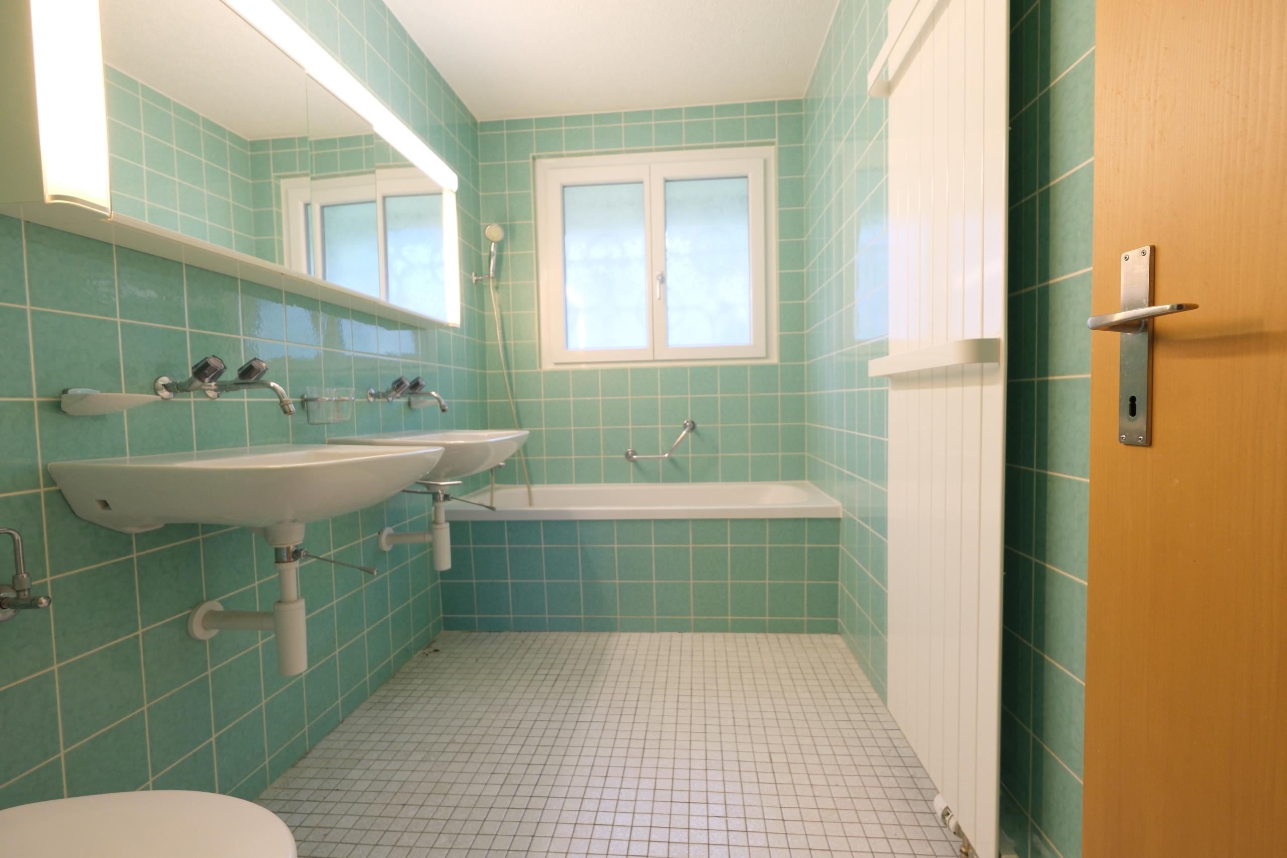 Badezimmer mit türkisfarbenen Fliesen und Doppelwaschbecken