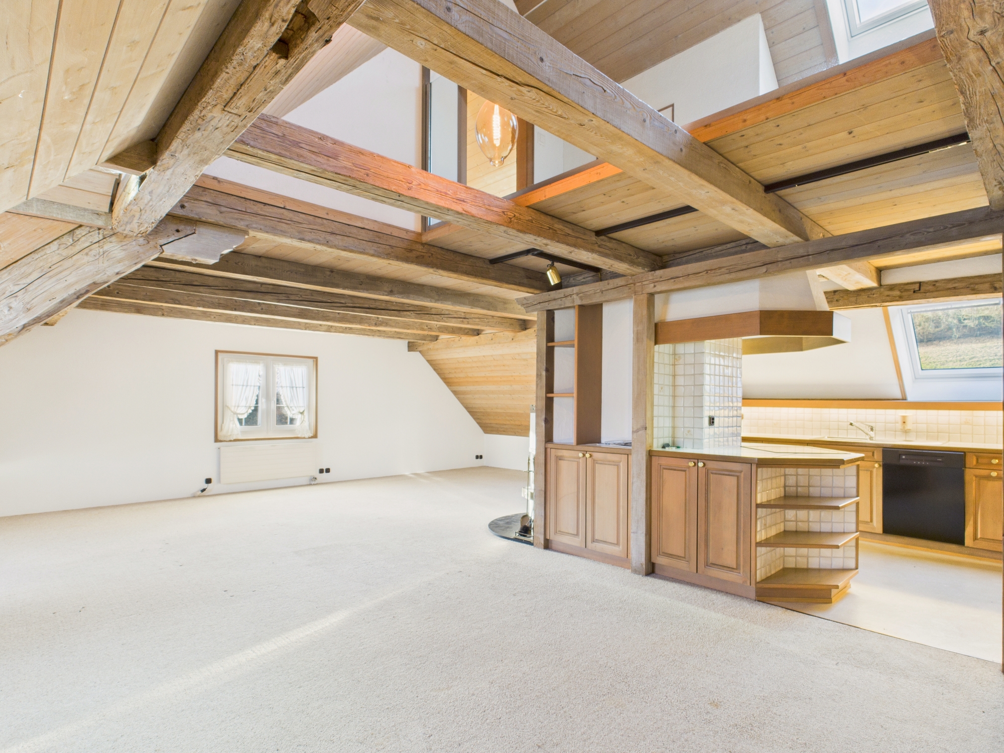 Offener Wohnbereich mit sichtbarer Küche und Holzbalkendecke