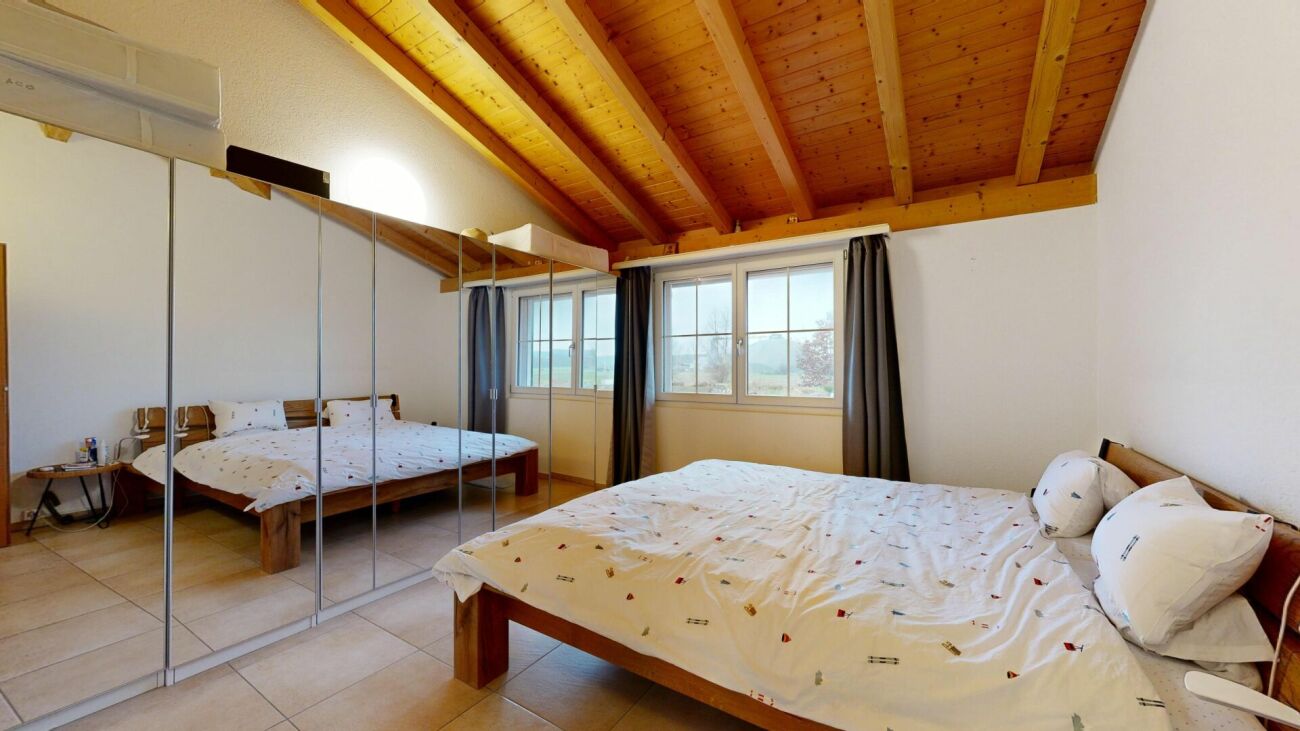 Dachgeschoss-Schlafzimmer mit Holzdecke und Spiegelkleiderschrank