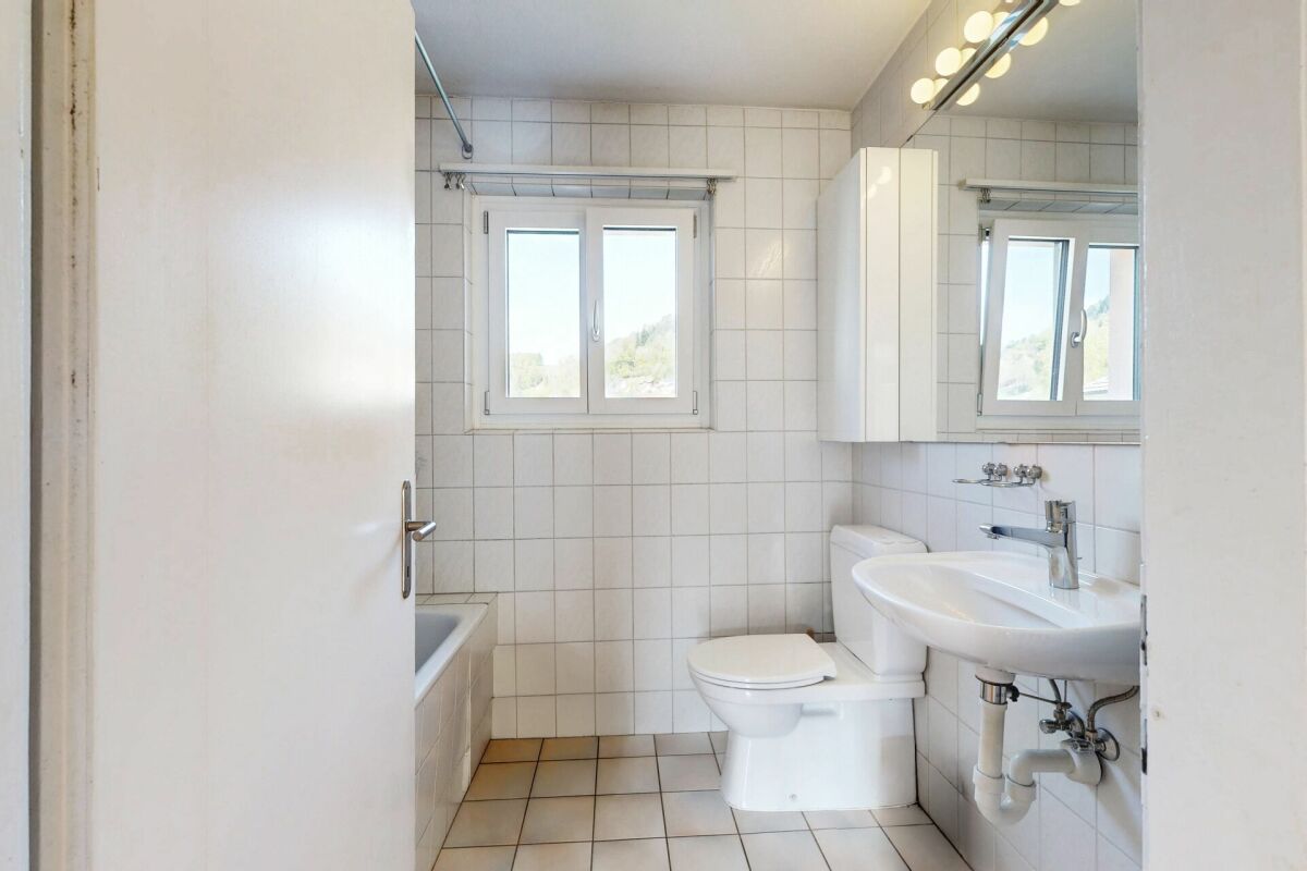 Helles kleines Badezimmer mit Fenster, Badewanne, WC und Waschbecken