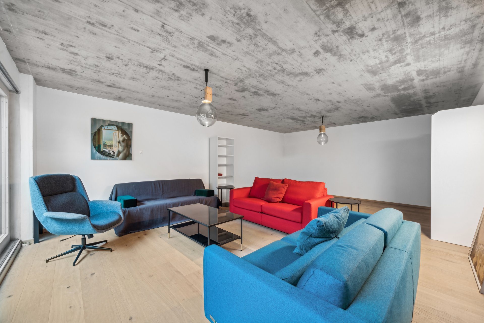 Modernes Wohnzimmer mit farbigen Sofas und Sichtbetondecke