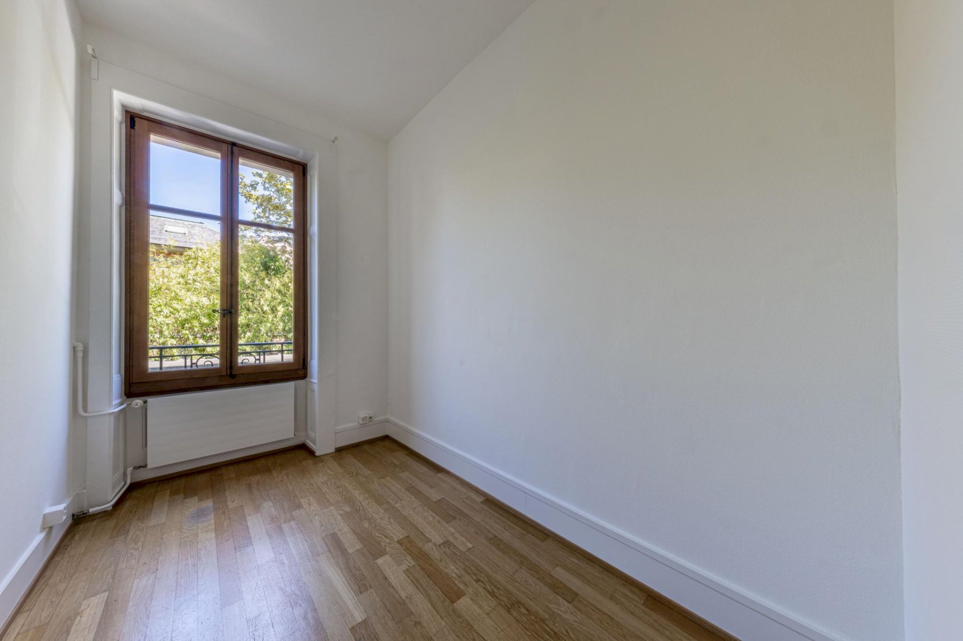 Helles kleines Zimmer mit Holzfenster und Parkettboden