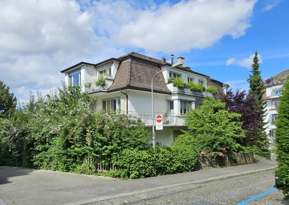 Wohnhaus mit Mansarddach und üppiger Bepflanzung