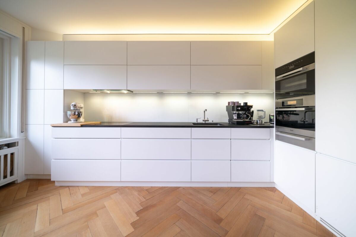 Moderne weiße Küche mit Holzparkett