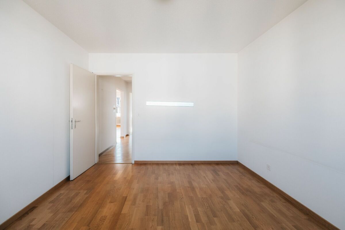 Leerer heller Raum mit Holzboden und offener Tür