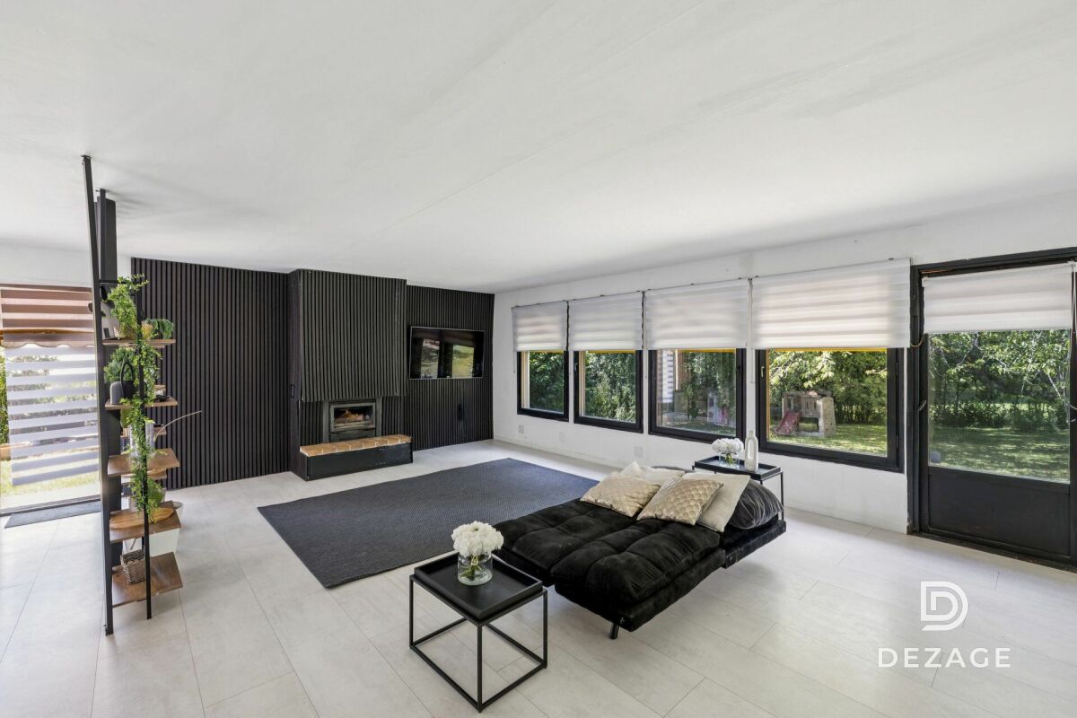 Modernes Wohnzimmer mit Kaminwand und großen Fenstern