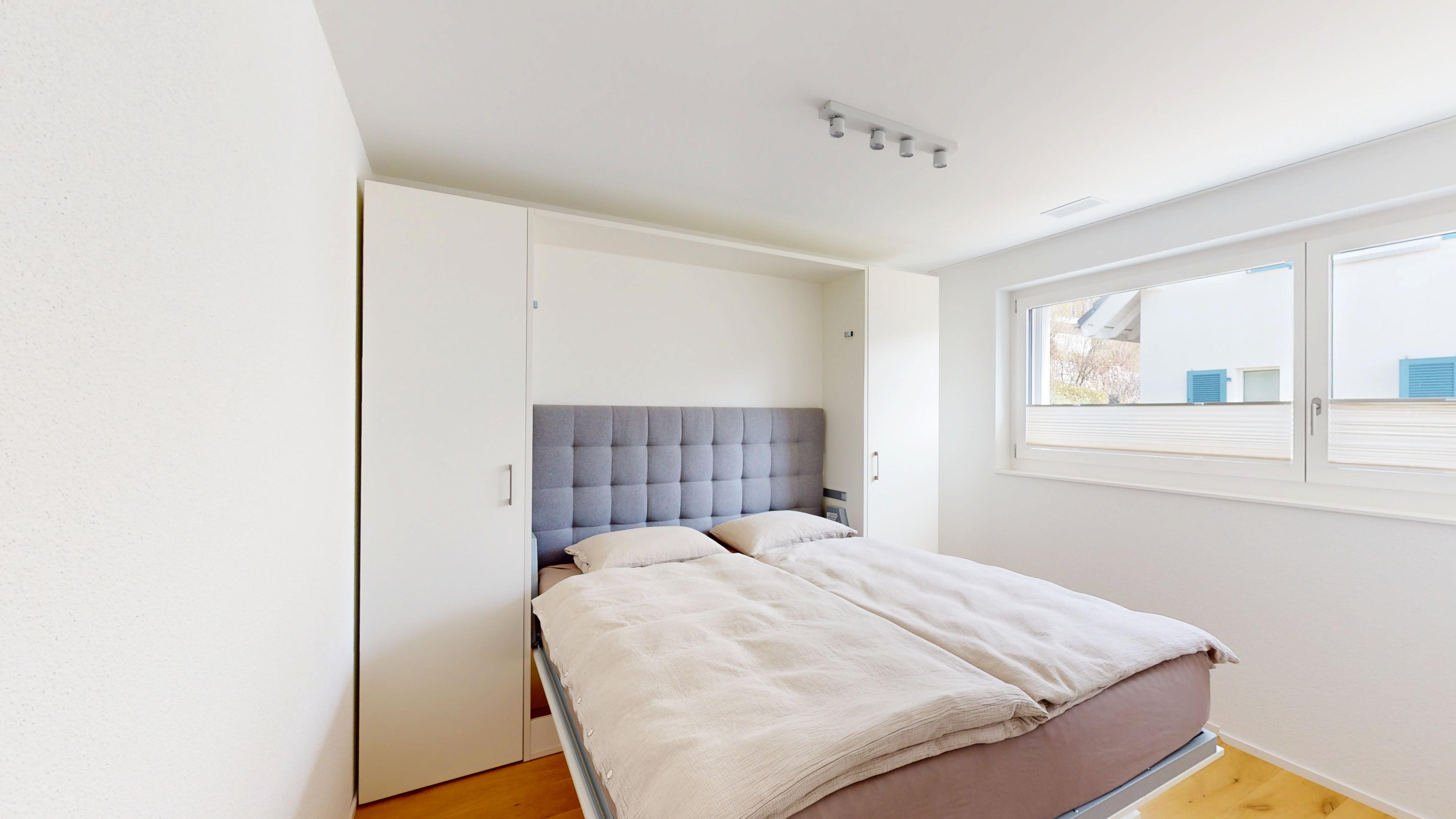 Helles Schlafzimmer mit eingebautem Bett und Schrankwand