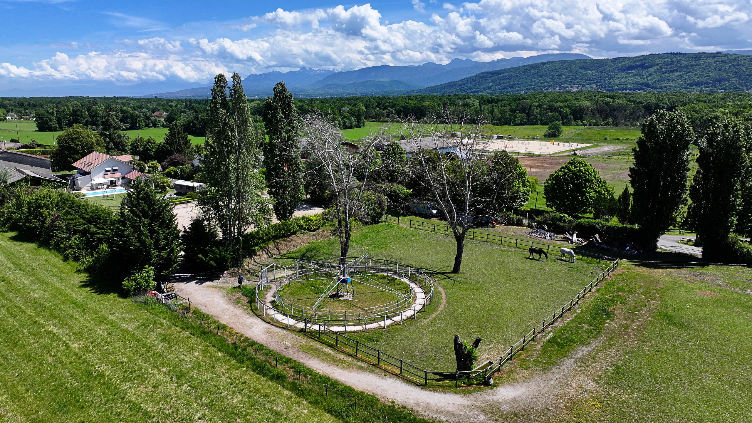 Ländliche Luftaufnahme mit Weide, Reitplatz und Bergpanorama