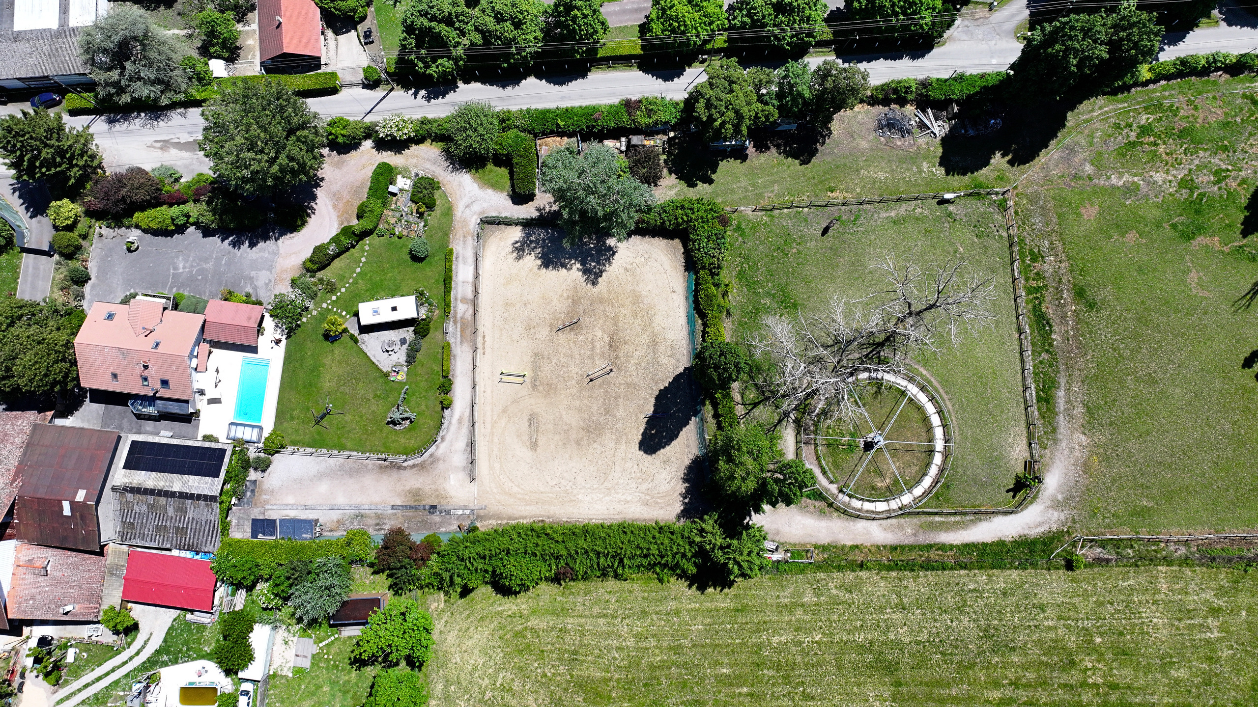Luftaufnahme eines großen Grundstücks mit Reitplatz, Pool und Wohnhaus
