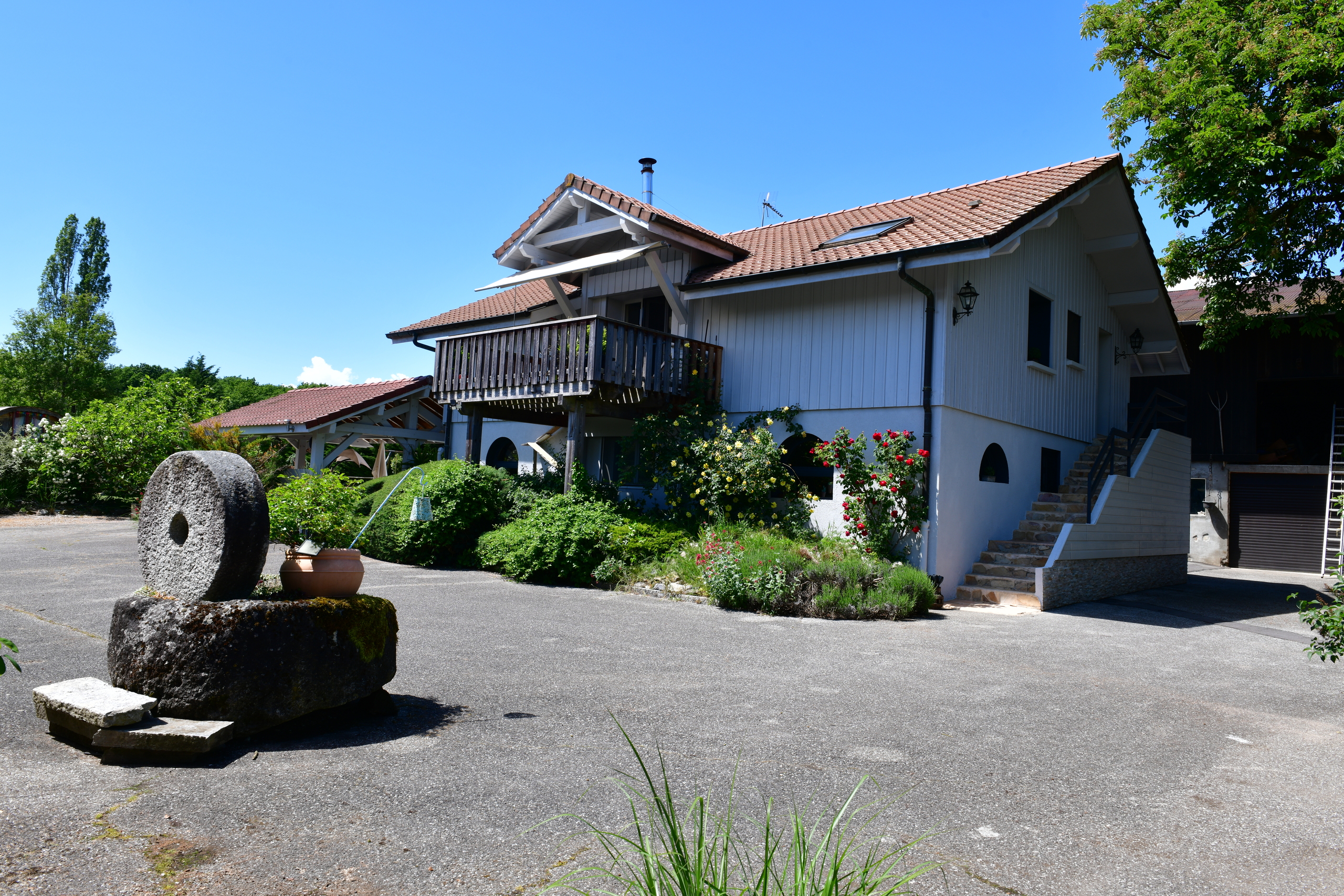 Außenansicht eines ländlichen Wohnhauses mit Balkon und Garten