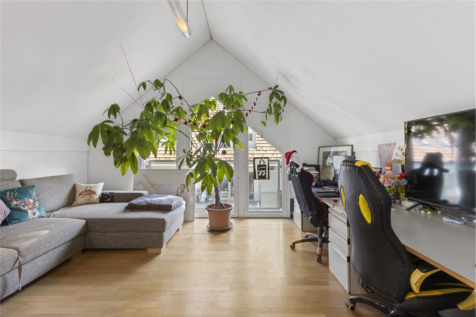 Dachgeschoss-Wohnraum mit Sofa und Arbeitsbereich