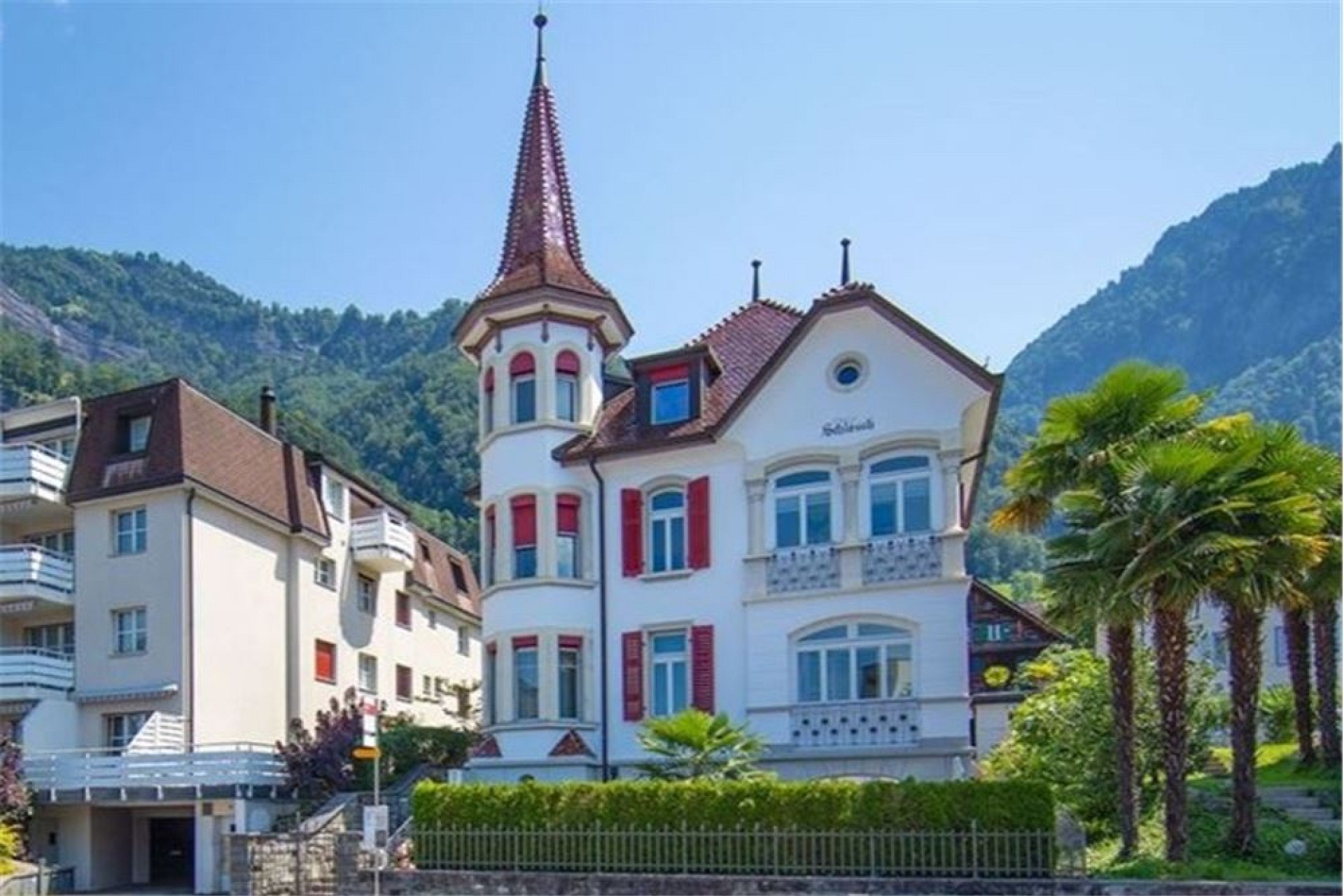 Historisches Villengebäude mit Turm vor Bergkulisse