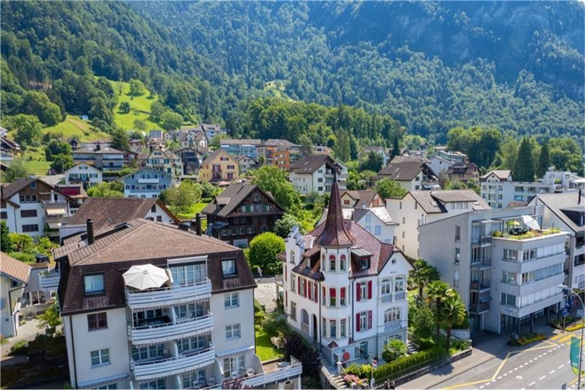 Städtische Wohnhäuser vor bewaldeter Bergkulisse