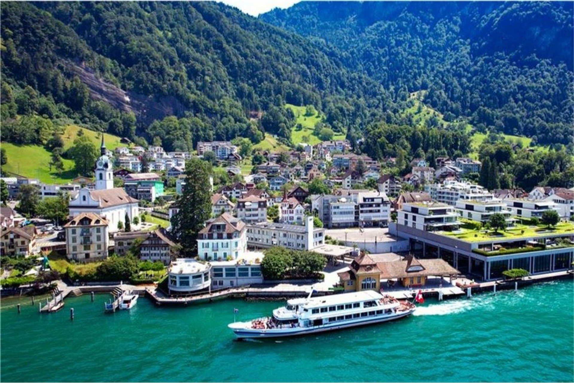 Luftaufnahme einer Seeuferstadt vor Bergkulisse