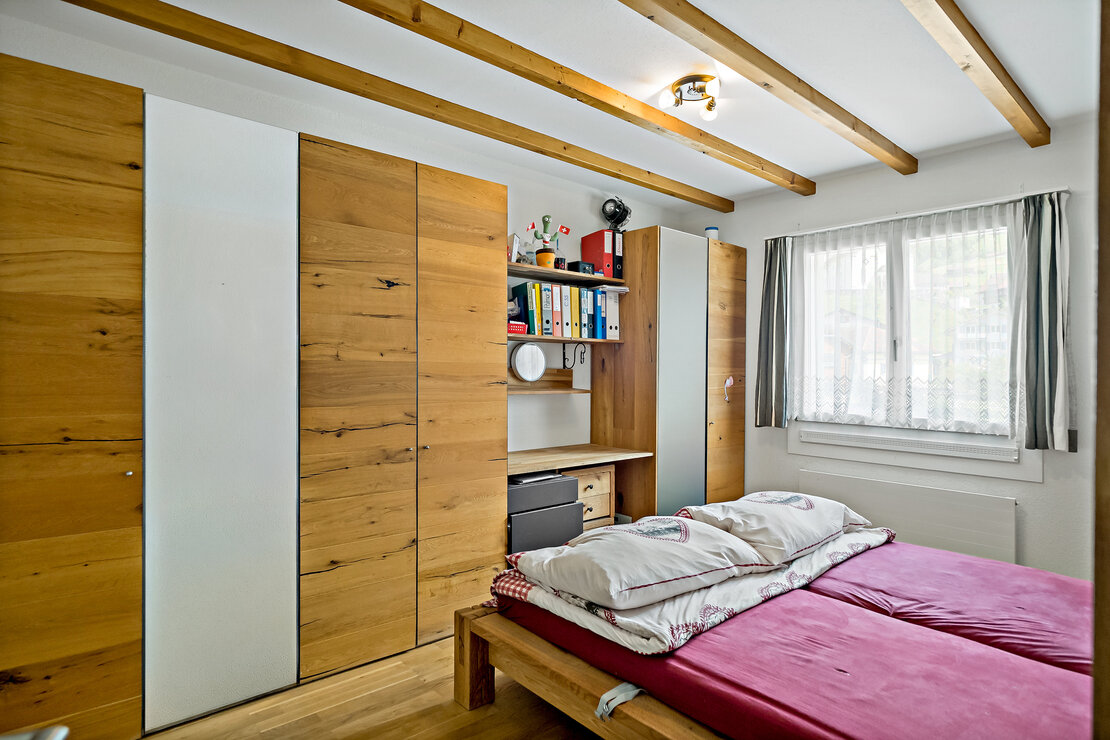 Helles Schlafzimmer mit Holzmöbeln und sichtbaren Deckenbalken