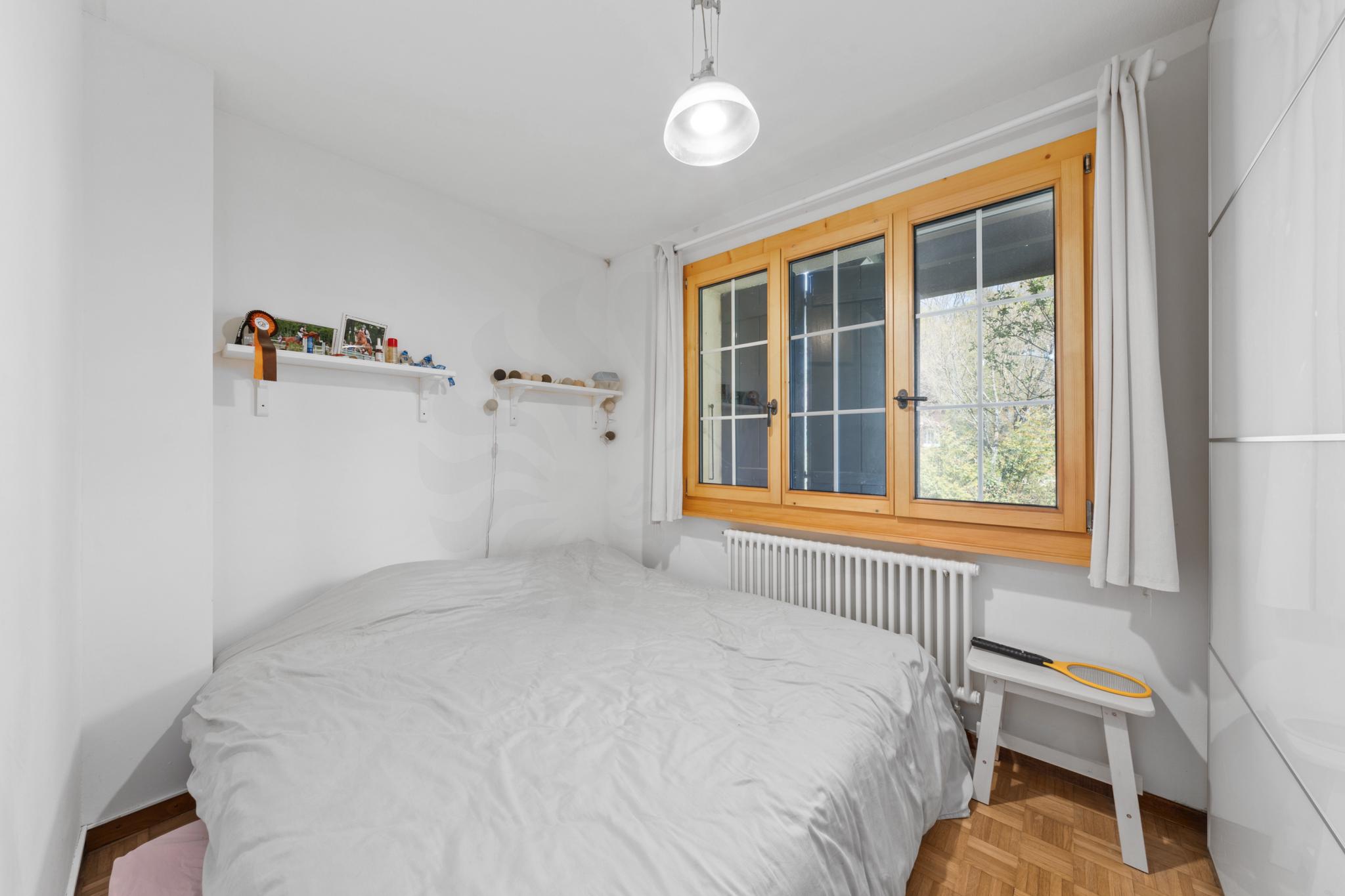 Helles Schlafzimmer mit Holzfenster und weißen Wänden