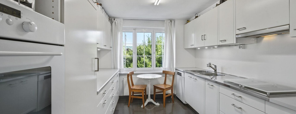 Helle weiße Einbauküche mit Fensterplatz
