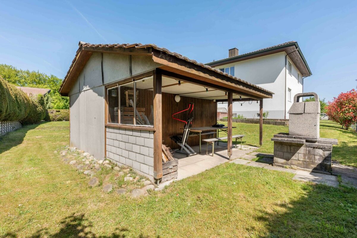Außenansicht eines Gartens mit kleinem Anbau und Überdachung