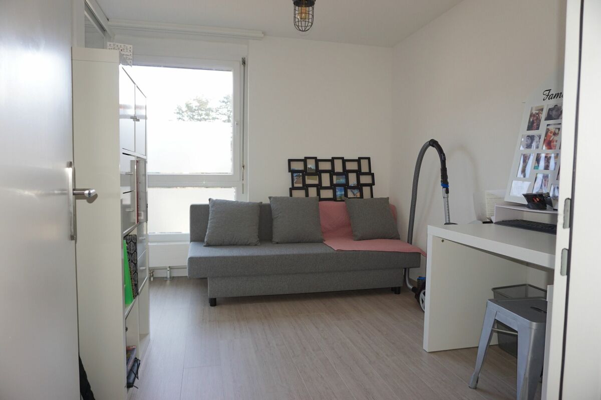 Kleines helles Zimmer mit Sofa und Schreibtisch