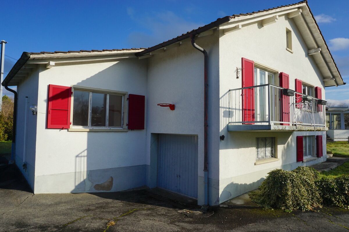 Außenansicht eines Wohnhauses mit Balkon und roten Fensterläden