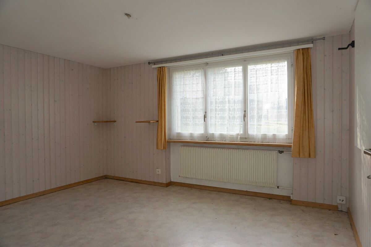Leeres, helles Zimmer mit Fenster und Heizkörper