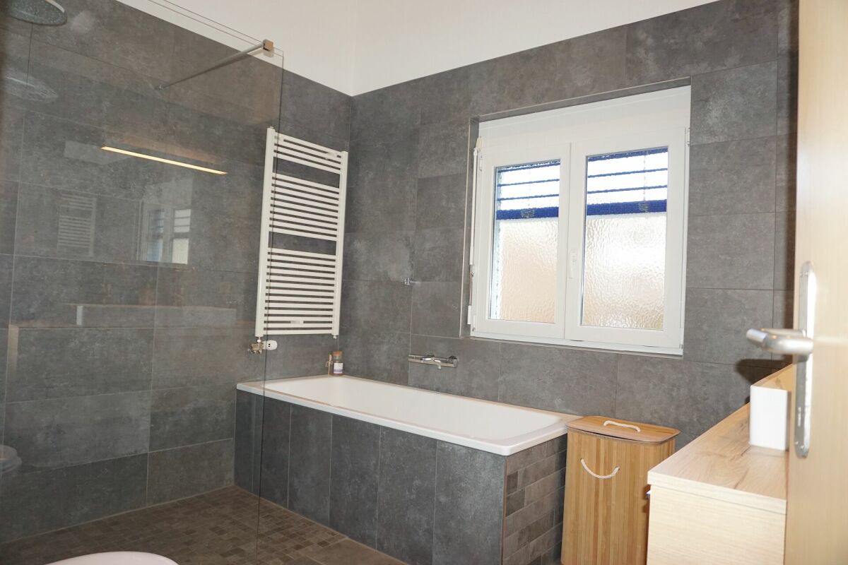 Modernes Badezimmer mit grauen Fliesen und Badewanne