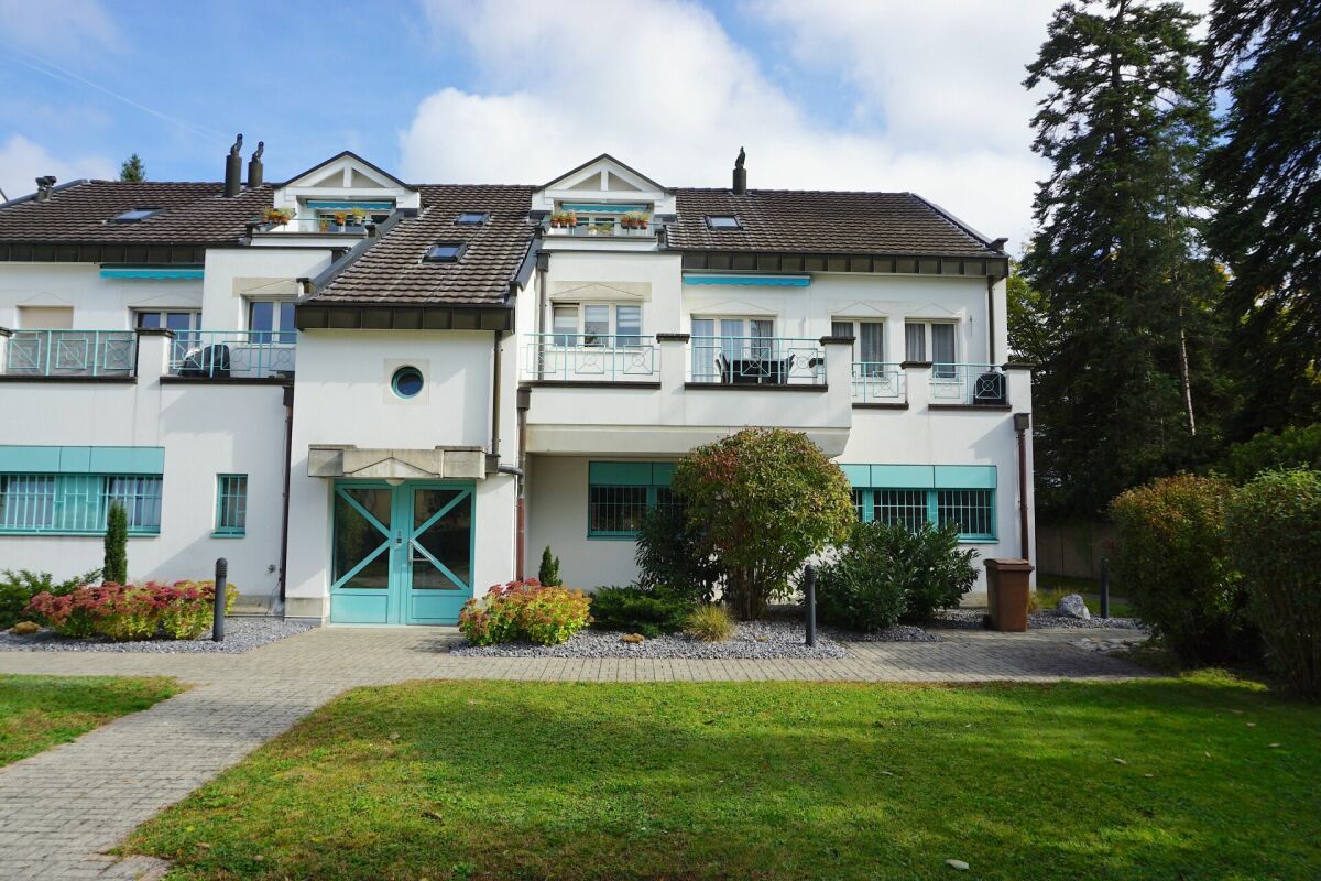 Mehrfamilienhaus mit heller Fassade und türkisfarbenen Akzenten
