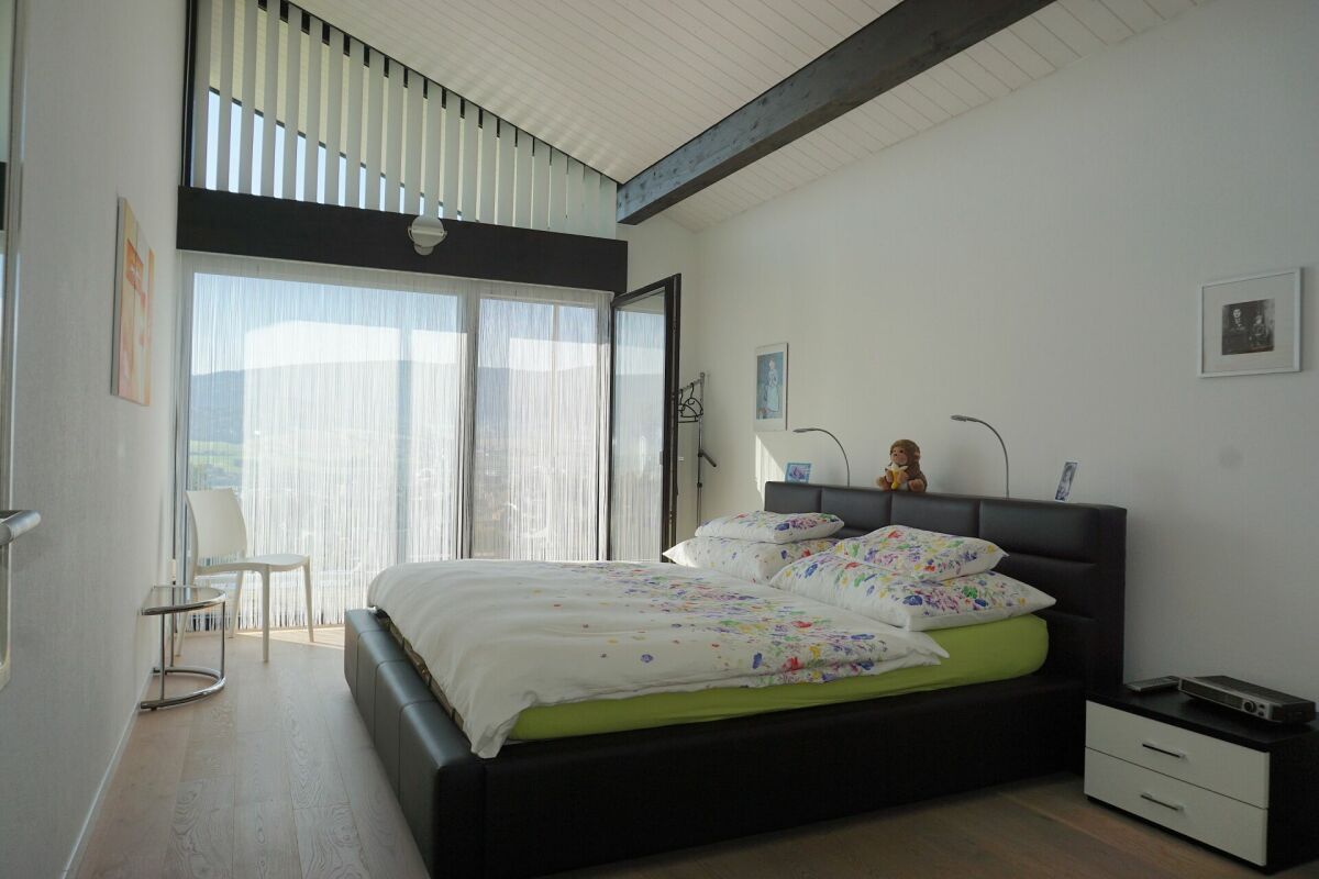 Helles Schlafzimmer mit großer Fensterfront und Bett