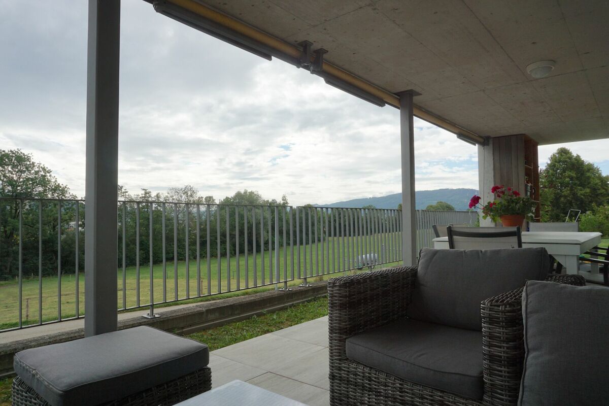 Überdachte Terrasse mit Lounge-Möbeln und Landschaftsblick