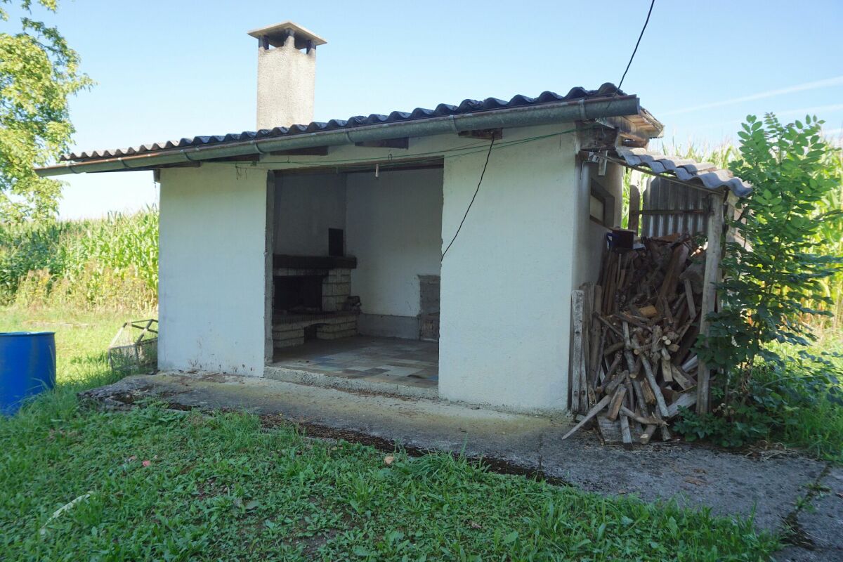 Außenansicht eines kleinen Gartenhauses mit Kamin und Holzlager