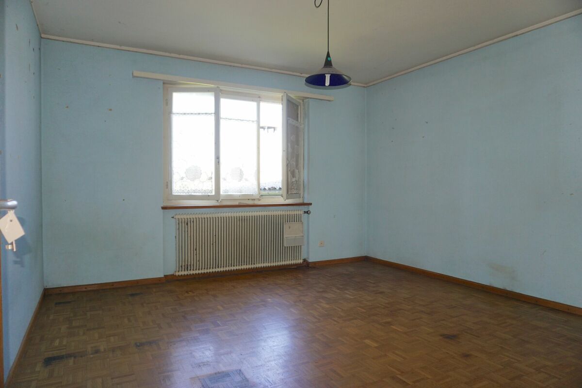 Leeres, renovierungsbedürftiges Zimmer mit Fenster und Heizkörper