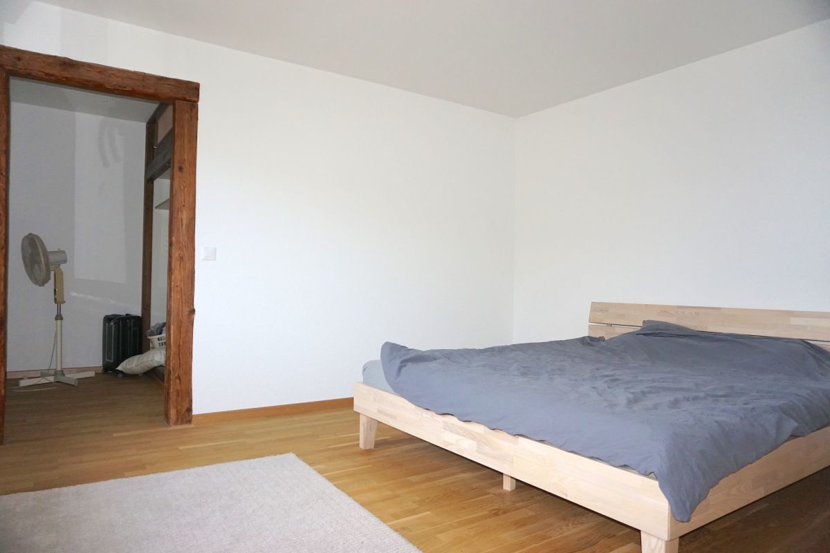 Schlafzimmer mit Holzbett und sichtbarem Nebenraum