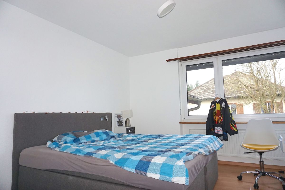Schlichtes Schlafzimmer mit Bett und Fenster
