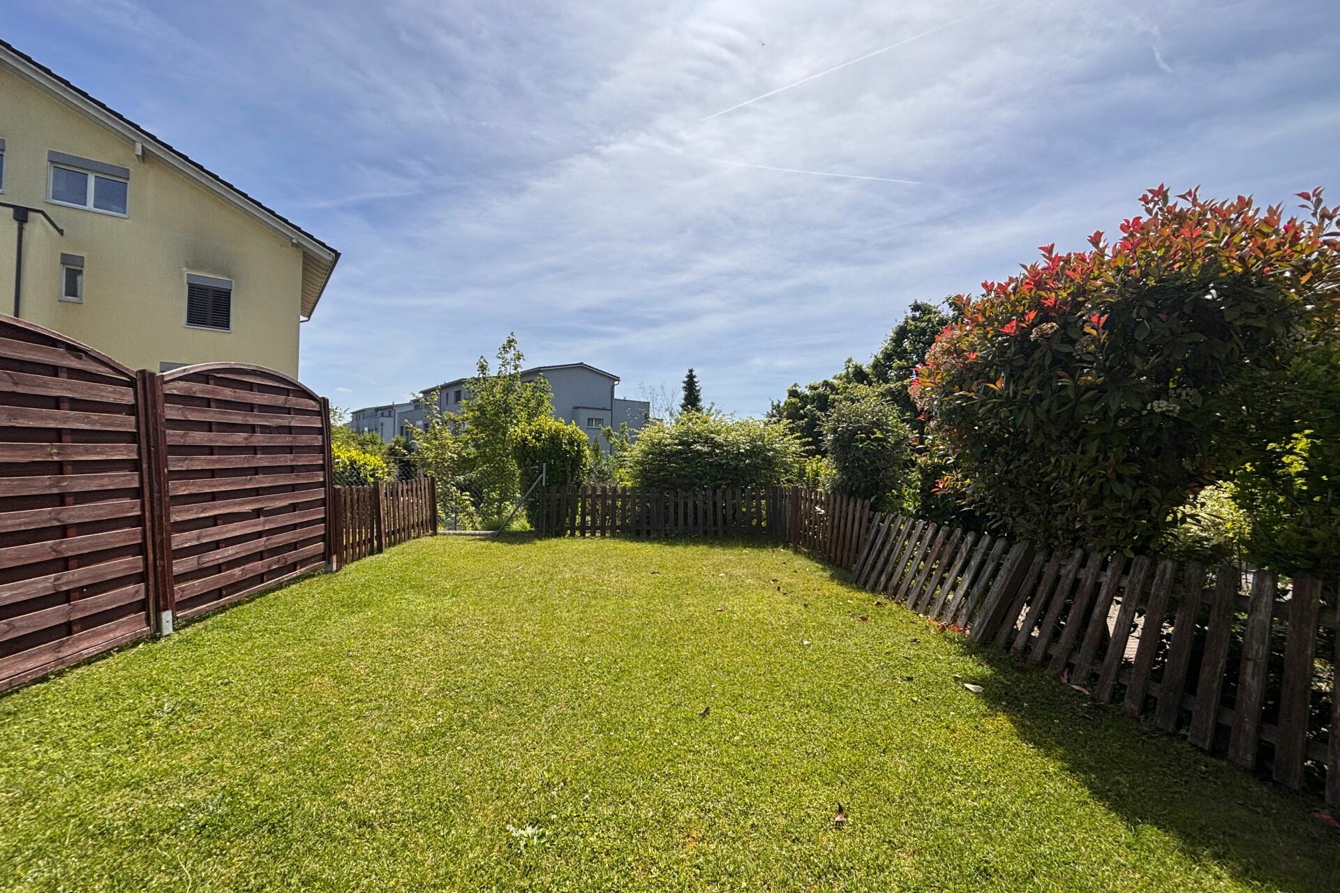 Garten mit Zaun und Nachbarhäusern