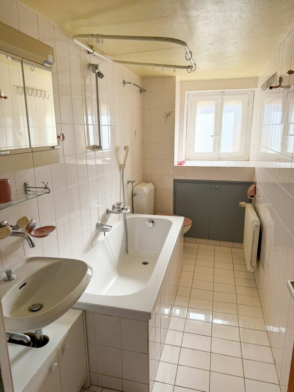 Helles Badezimmer mit Badewanne und Fenster