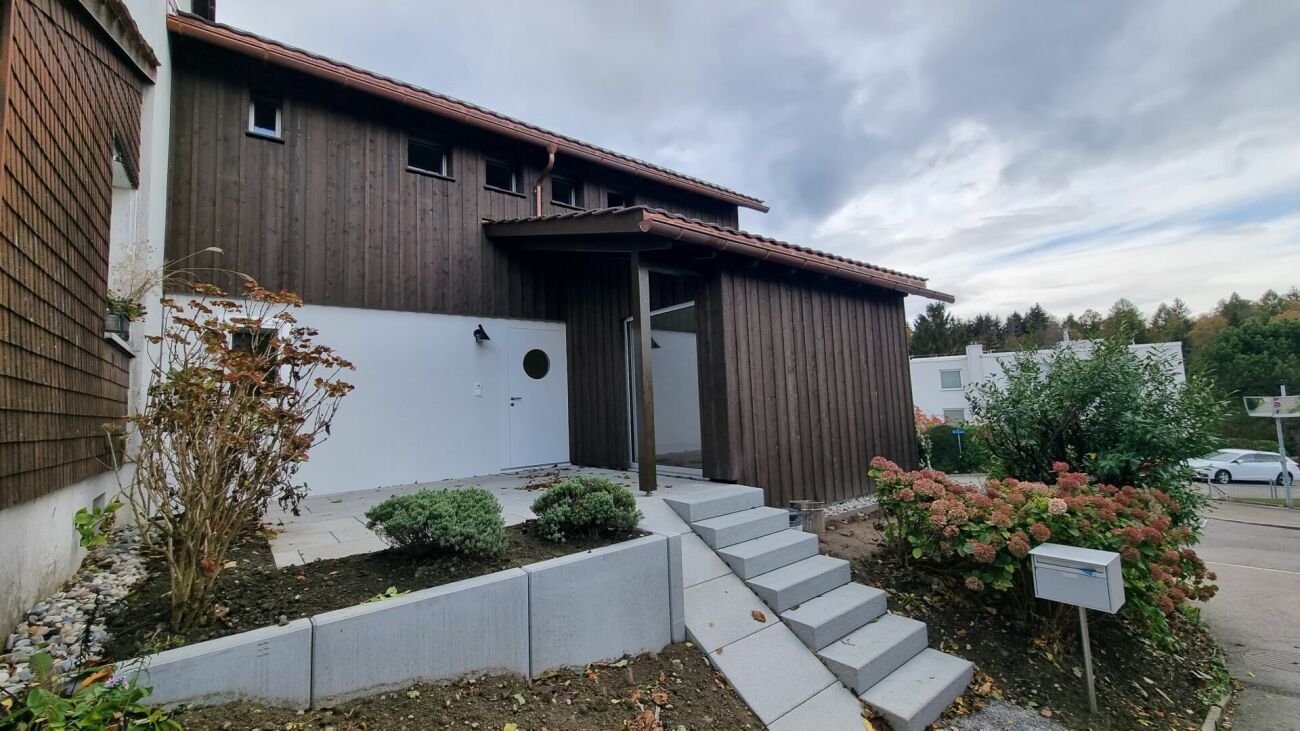Außenansicht eines Holzhauses mit Garten und Zugangstreppe