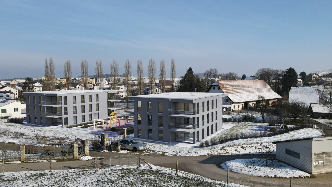 Schneebedeckte Wohnanlage mit zwei modernen Mehrfamilienhäusern